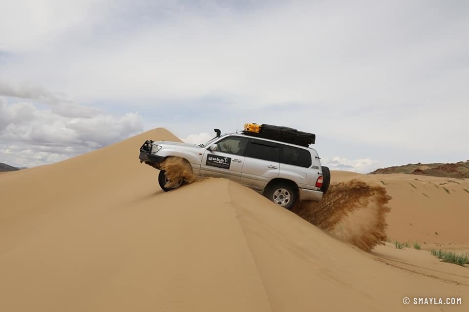 Un 4x4 franchit la crête d'une dune